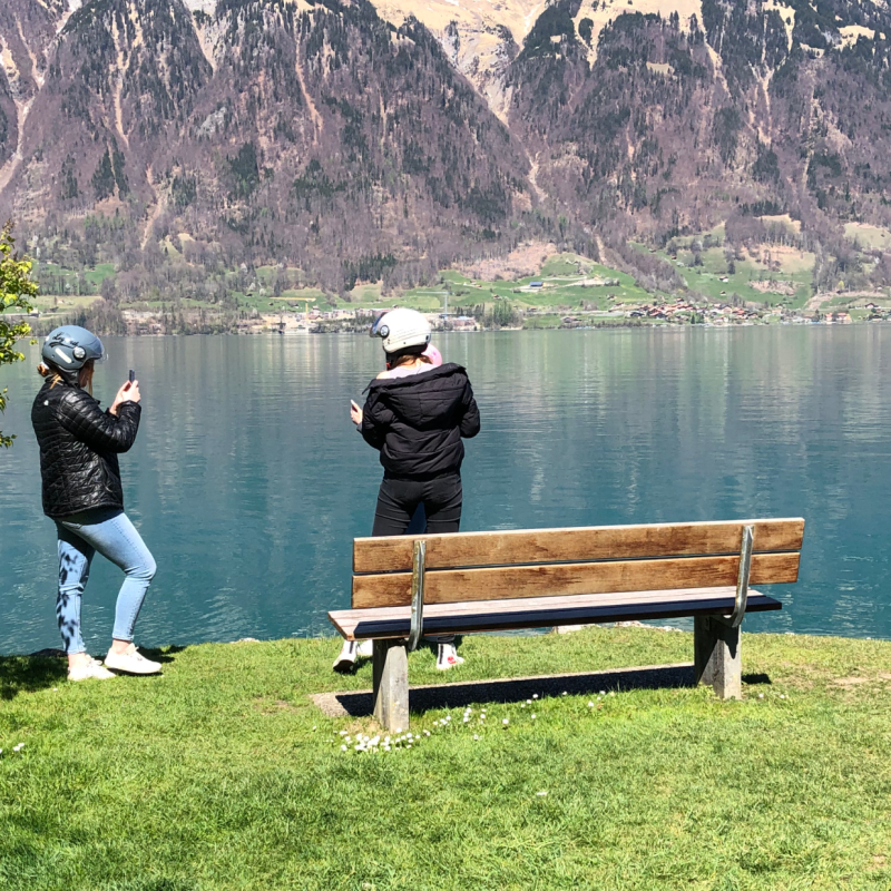two girls wearing helmets near a lake