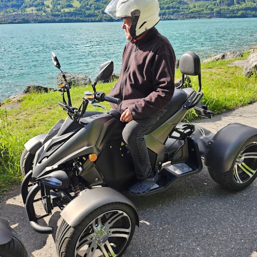 a man riding a motorcycle on the side of a lake